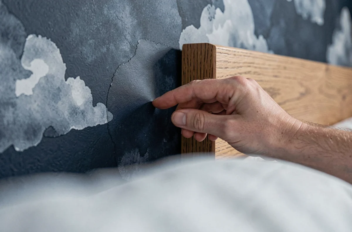 Pose de papier peint bleu marine en tête de lit lors d'une transformation de chambre adulte sans travaux
