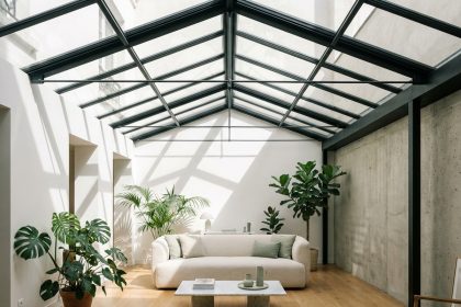 Verrière métallique intégrée dans un salon moderne style parisien avec sol en chêne clair et plantes tropicales